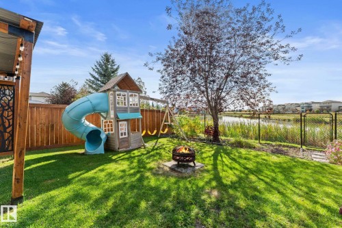 Expansive backyard featuring a manicured lawn, established tree, and a decorative fire pit - #5 4900 62 St, Beaumont, AB 