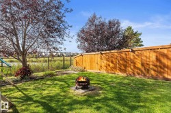 Grassed backyard featuring a wood fence, mature trees, and a chain-link fence bordering a pond - 