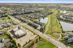Expansive aerial capturing residential properties, paved roads, and multiple bodies of water - 