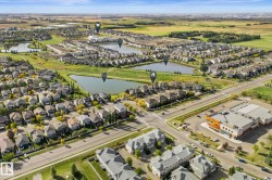 Aerial perspective of a residential community with multiple water features, established roadways, and commercial buildings - 