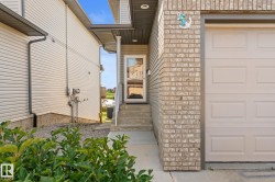 Brick facade with white garage door, concrete steps, and a glass-paneled entry door - 
