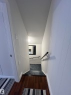 Rich wood-finish flooring transitioning to carpeted stairs with a handrail - 