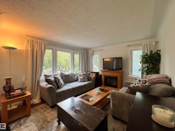 Living area featuring a fireplace with a wood surround, large window, and tiled flooring - 
