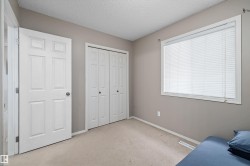 Neutral wall paint with carpet flooring, featuring a large window with blinds, and white bi-fold closet doors - 