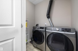 Dedicated utility space featuring a front-loading washer and dryer set, neutral wall color, and durable flooring - 