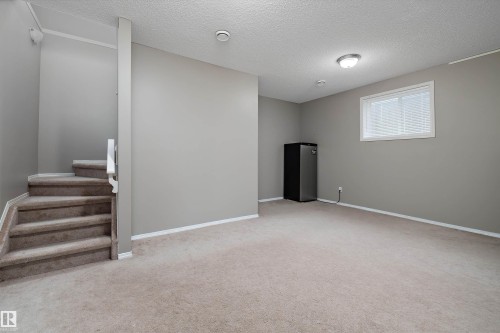 Carpeted flooring extending into a carpeted staircase with white handrail - 3114 32 Avenue Nw, Edmonton, AB 