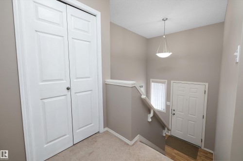 Entryway featuring a pendant light fixture, white paneled door, and wood-finish flooring - 3114 32 Avenue Nw, Edmonton, AB 