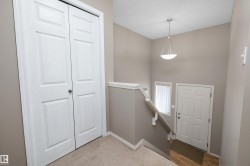 Entryway featuring a pendant light fixture, white paneled door, and wood-finish flooring - 