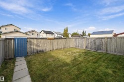 Expansive backyard featuring a manicured lawn, full wood fencing, and a stone-paver pathway leading to a blue wooden gate - 