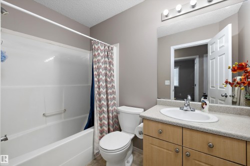 Built-in bathtub with shower, toilet, and a wood-finish vanity with an integrated sink - 3114 32 Avenue Nw, Edmonton, AB 