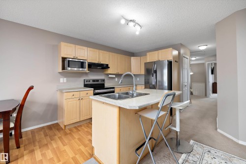 Kitchen featuring light wood-finish cabinetry, stainless steel appliances, a center island with sink, and light-toned countertops - 3114 32 Avenue Nw, Edmonton, AB 