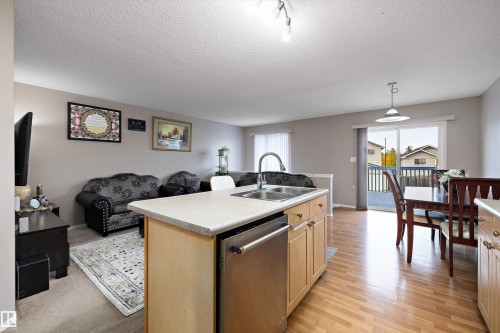 Open-concept living space featuring an island kitchen with a double basin sink, light wood-finish cabinetry, and an integrated dishwasher - 3114 32 Avenue Nw, Edmonton, AB 