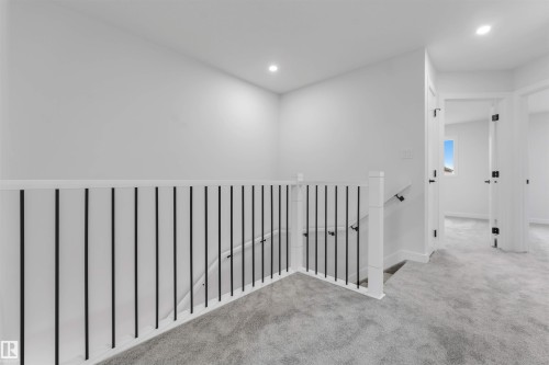 Light gray carpeting throughout, white walls, black metal balusters, white handrail, and recessed lighting - 523 Robinson Blvd, Leduc, AB 