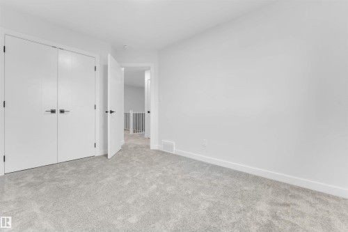 Plush gray carpeting, white walls, white trim, and white closet doors with black hardware - 523 Robinson Blvd, Leduc, AB 