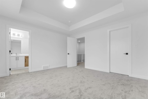 Recessed ceiling design, light grey carpeting, white interior doors, matte black door hardware, built-in vanity with dual-tone cabinetry - 523 Robinson Blvd, Leduc, AB 
