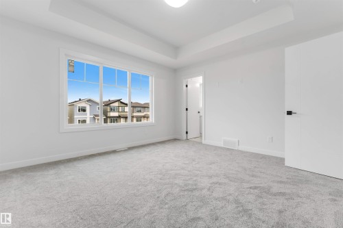 Recessed ceiling detail, light gray carpeting, expansive window, white paneled doors, and black hardware - 523 Robinson Blvd, Leduc, AB 