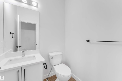 Vanity with white cabinets, undermount sink, chrome faucet, and rectangular mirror - 523 Robinson Blvd, Leduc, AB 