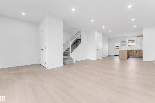 Spacious room with light wood-finish flooring, recessed lighting, and a neutral wall palette - 523 Robinson Blvd, Leduc, AB 