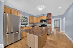 Kitchen featuring wood cabinetry, stainless steel appliances, a wood-finish island with a butcher block style countertop, and hardwood flooring - 