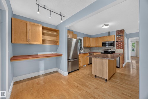 Wood-finish flooring throughout, with a kitchen island featuring a wood-finish countertop - 9615 75 Avenue Nw, Edmonton, AB 