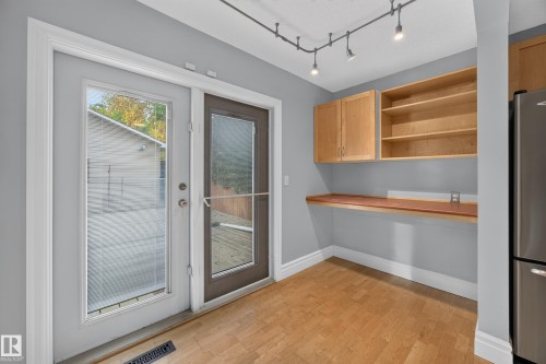 Wood-finish flooring, light wood cabinetry, built-in shelving, track lighting, and a built-in wood-finish countertop - 9615 75 Avenue Nw, Edmonton, AB 