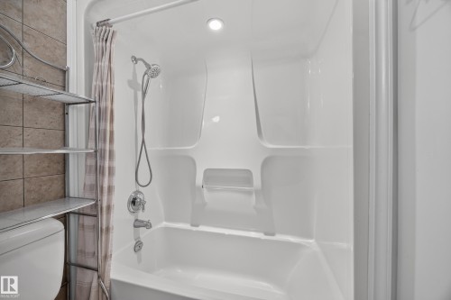 Integrated white fiberglass tub and shower enclosure with chrome fixtures - 9615 75 Avenue Nw, Edmonton, AB 