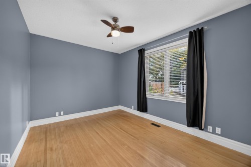 Wood-finish flooring with white trim, a ceiling fan, and a window with blinds - 9615 75 Avenue Nw, Edmonton, AB 
