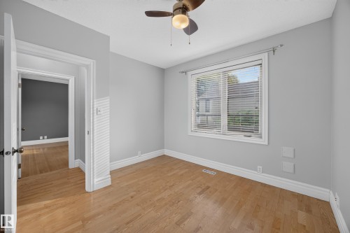 Wood-finish flooring, light grey wall paint, and a ceiling fan with integrated lighting - 9615 75 Avenue Nw, Edmonton, AB 