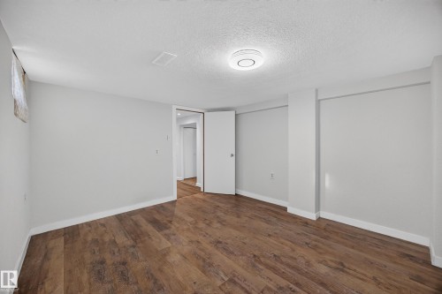 Wood-finish flooring, recessed ceiling light, white walls, and a white door - 9615 75 Avenue Nw, Edmonton, AB 