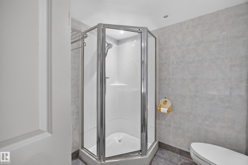 Glass-enclosed corner shower with a polished chrome frame, white shower base, and integrated shelving - 9615 75 Avenue Nw, Edmonton, AB 
