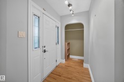 Entryway featuring wood-finish flooring, a white paneled entry door with sidelight windows, and an arched alcove - 