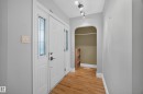 Entryway featuring wood-finish flooring, a white paneled entry door with sidelight windows, and an arched alcove - 9615 75 Avenue Nw, Edmonton, AB 