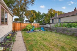 Side yard featuring a concrete pathway, manicured lawn, and wood privacy fencing - 