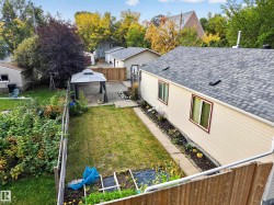 Spacious backyard featuring a manicured lawn, paved patio area with gazebo, and perimeter fencing - 
