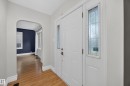 Entryway featuring a white paneled door with decorative glass sidelites, wood-finish flooring, and an arched doorway - 9615 75 Avenue Nw, Edmonton, AB 