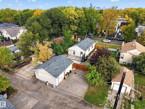 Property featuring a detached garage with a shingled roof, a fenced backyard, and mature trees - 9615 75 Avenue Nw, Edmonton, AB 