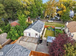 Expansive backyard featuring a manicured lawn, established garden beds, a gravel patio, and a wood deck - 