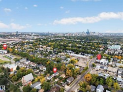 Aerial perspective showcasing an urban skyline in the background, residential areas with mature trees, commercial buildings, and paved roadways - 