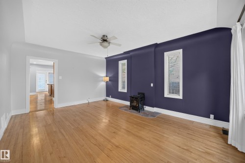 Hardwood flooring, ceiling fan, and a built-in fireplace with a stone hearth - 9615 75 Avenue Nw, Edmonton, AB 