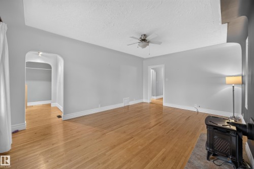 Hardwood flooring, arched doorways, ceiling fan, and a cast iron stove - 9615 75 Avenue Nw, Edmonton, AB 