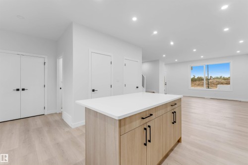 Kitchen island with a light wood-finish base, white countertop, and black hardware - 525 Robinson Blvd, Leduc, AB 