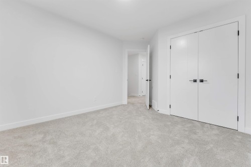 Light gray carpeting, white walls, and white double-door closet with dark hardware - 525 Robinson Blvd, Leduc, AB 