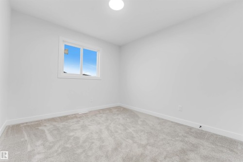 Light-colored carpeting, white painted walls, and a single window with white trim - 525 Robinson Blvd, Leduc, AB 