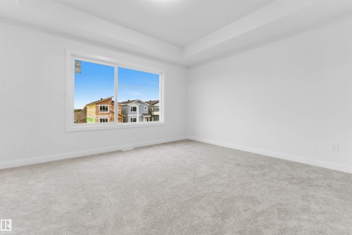 Spacious room with light gray carpeting and a large window - 525 Robinson Blvd, Leduc, AB 