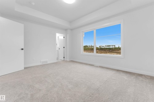 Spacious room featuring light-colored carpeting, white walls, a large window, and recessed lighting - 525 Robinson Blvd, Leduc, AB 