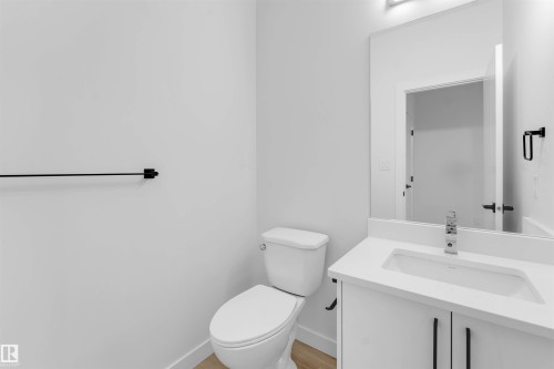 White vanity with an integrated sink and chrome faucet, rectangular mirror, and matte black hardware - 525 Robinson Blvd, Leduc, AB 