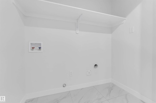 Laundry area featuring a built-in shelf, marble-look tile flooring, and dedicated appliance connections - 525 Robinson Blvd, Leduc, AB 