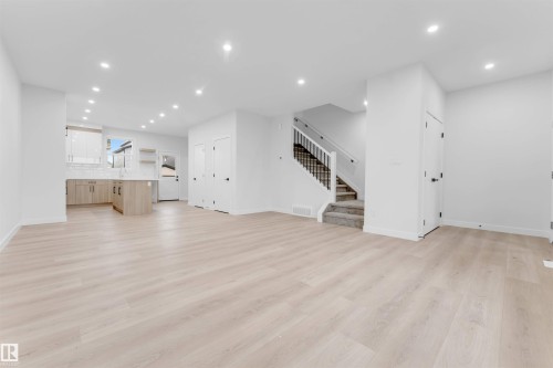 Open-concept living area featuring light wood-finish flooring, recessed lighting, and a modern kitchen with light wood-finish cabinetry - 525 Robinson Blvd, Leduc, AB 
