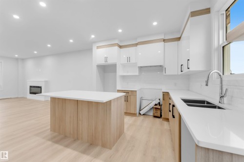Open-concept kitchen with a central island, light wood-finish flooring, white cabinetry, and recessed lighting - 525 Robinson Blvd, Leduc, AB 
