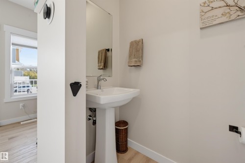 Pedestal sink with chrome faucet, large vanity mirror, and light wood-finish flooring - #3 150 Everitt Dr N, St. Albert, AB 